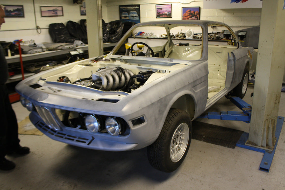 BMW E9 in need of restoration, featuring a classic coupe design with visible signs of aging and wear. The image highlights the car's vintage styling and the areas requiring attention for a full restoration.