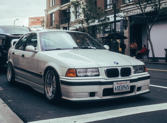 BMW E36 M3, featuring its sporty design with aggressive styling, distinct front grille, and classic alloy wheels. The image highlights the car’s performance-oriented features and iconic appearance.