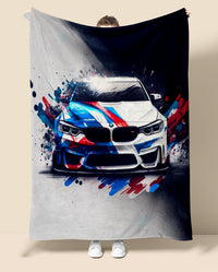 Person holding a blanket with a BMW M4 car design featuring splashes of red, blue, and white.