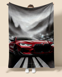Person holding a blanket with a red BMW car design on a neutral background