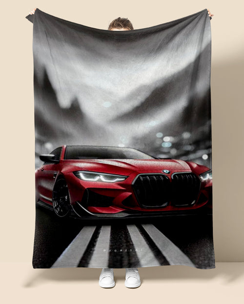 Person holding a blanket with a red BMW car design on a neutral background
