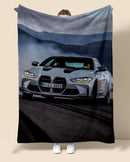 Person holding a blanket with a BMW M4 car design on a neutral background
