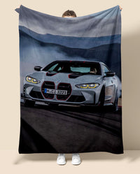 Person holding a blanket with a BMW M4 car design on a neutral background