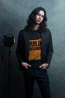 Person wearing a black blazer over an orange graphic t-shirt with text and design, standing against a dark background.