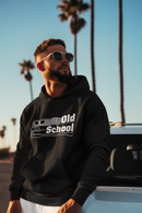 Man wearing a black hoodie with 'Old School' text, sunglasses, and white pants standing in front of palm trees.