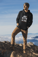 Person wearing a black hoodie with text  Just skill no tech, standing on a mountain with a blue sky and clouds in the background. Bavarian old school