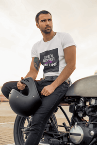 Man sitting on a motorcycle holding a helmet with a white t-shirt featuring text Life is better in the fast lane. Bavarian old school